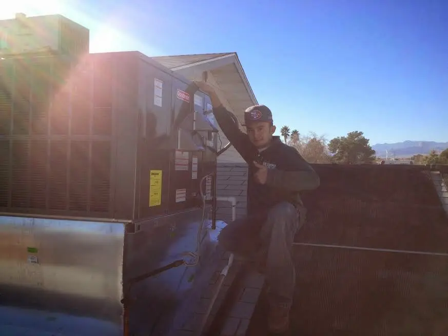HVAC technician performing Heat Pump Repair on a rooftop unit in Dryden