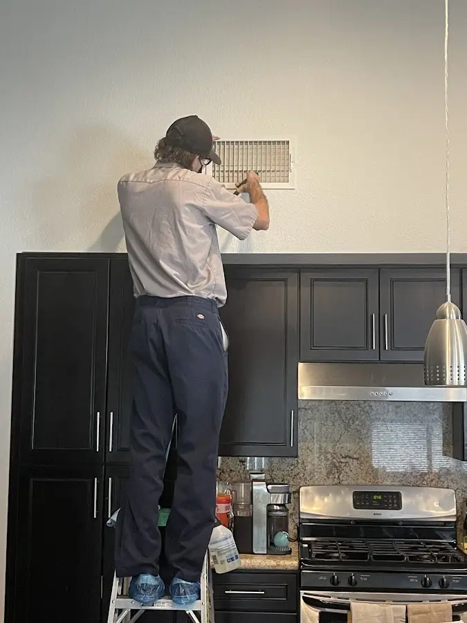 Technician inspecting an air vent during HVAC service in Dryden